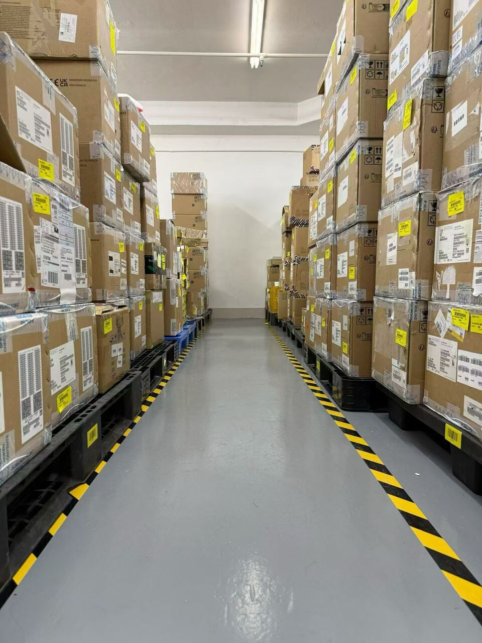 Storage aisle with labelled cardboard boxes stacked on pallets on both sides